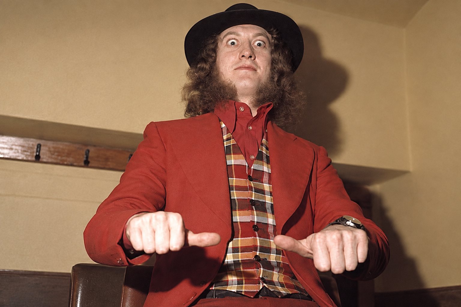 Noddy Holder performing onstage with Slade, singing into a microphone