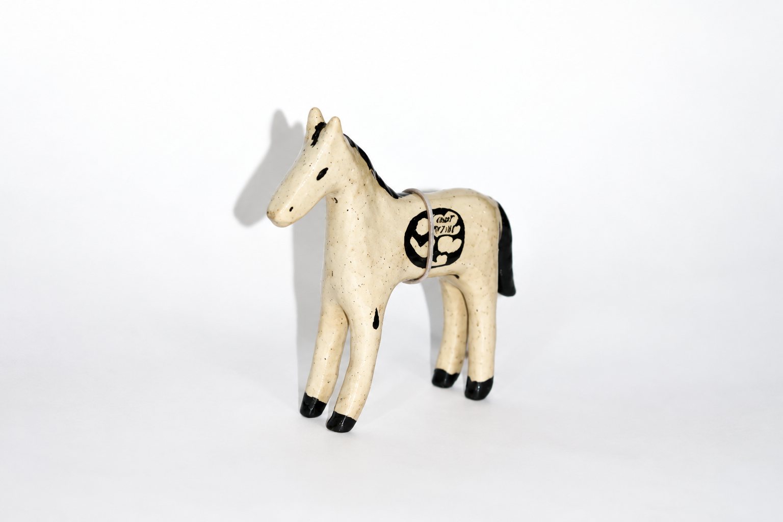 White hand-pinched ceramic jar by Gallina Clueka with a red circle and black running dogs