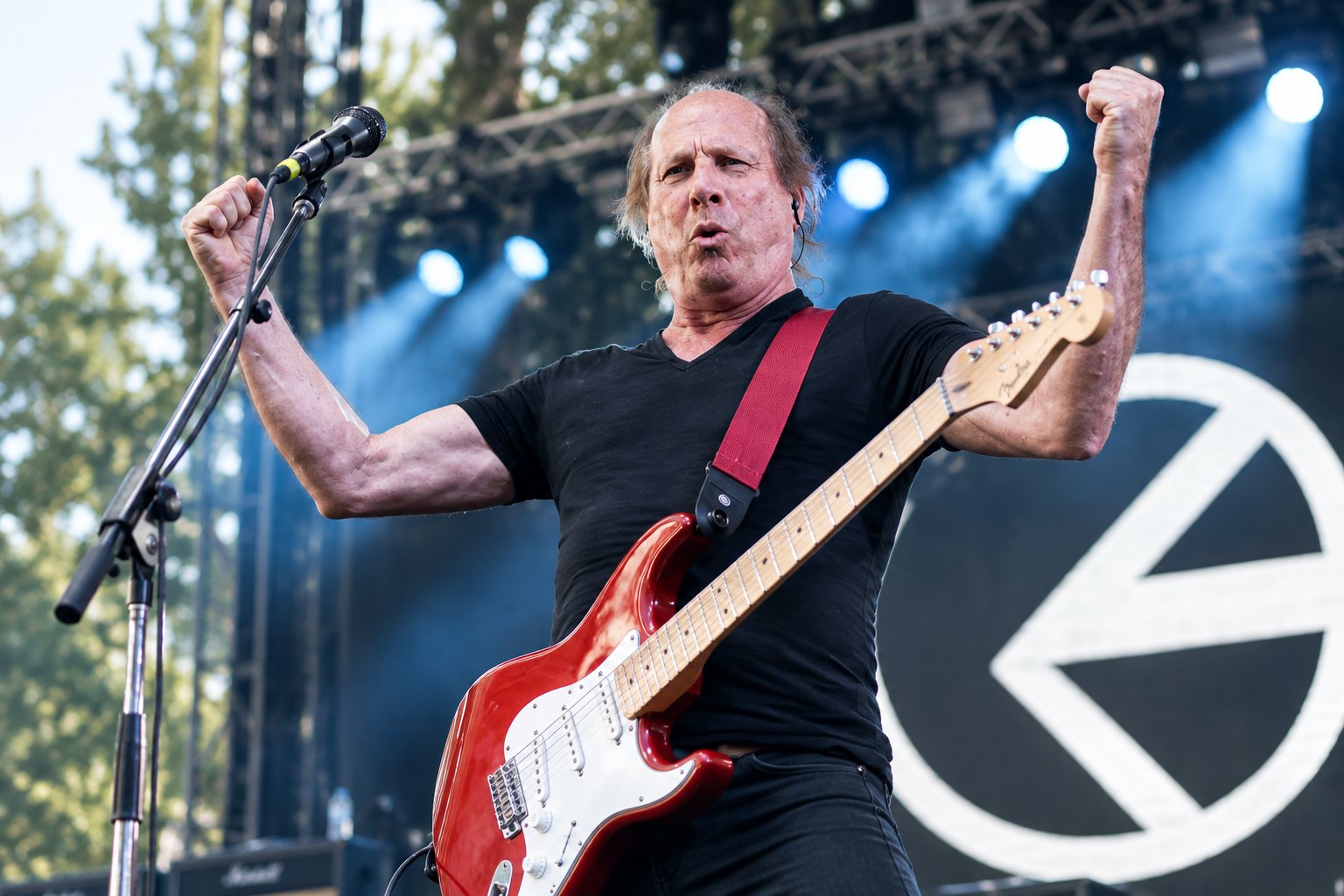 Adrian Belew playing electric guitar with an orchestra on stage